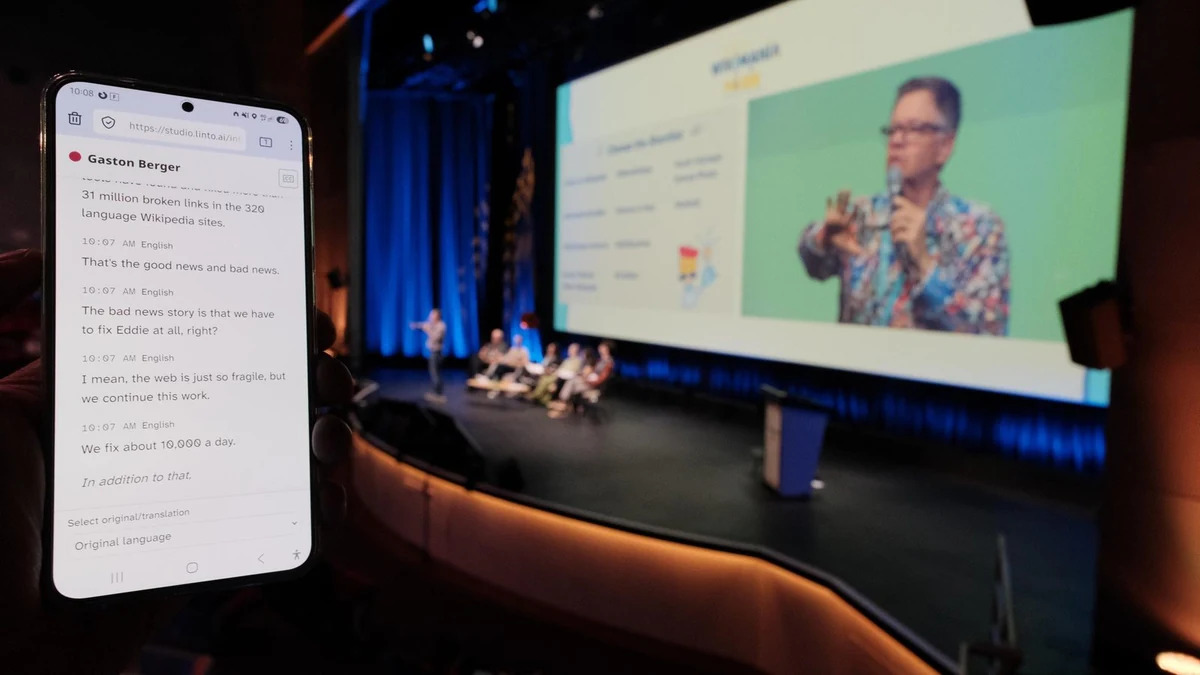 Un participant suit l'intervention sur son téléphone avec LinTO pendant que l'orateur est sur scène, à Wikimania 2026